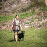 A woman is walking with her black labrador